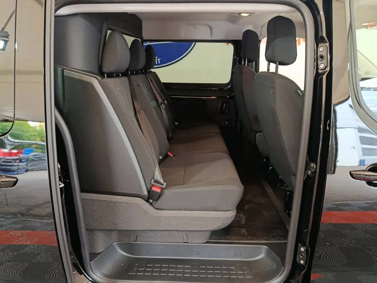 Vue latérale intérieure côté droit du Citroën Jumpy XL noir, montrant la banquette arrière trois places en tissu gris.