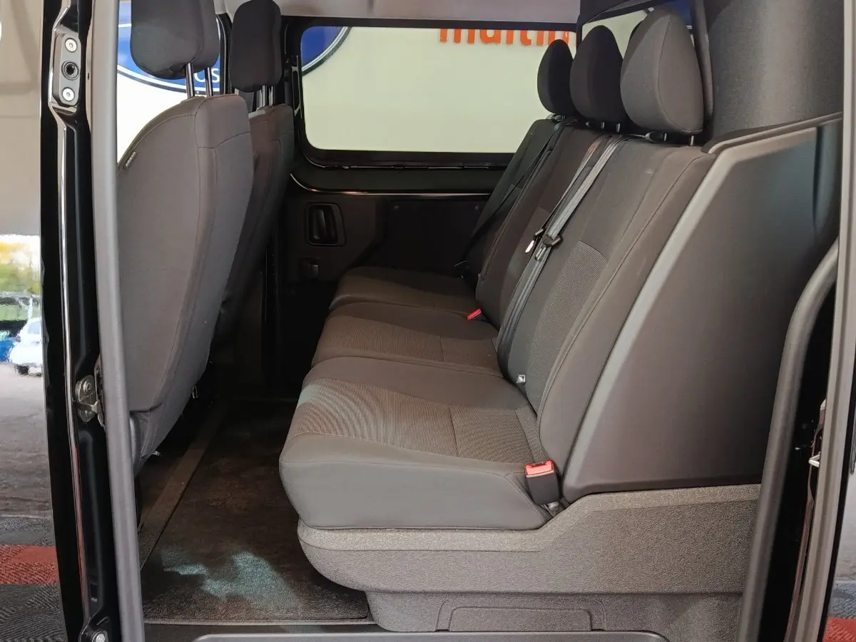 Vue latérale intérieure sur la banquette arrière grise du Citroën Jumpy XL noir avec portes ouvertes.