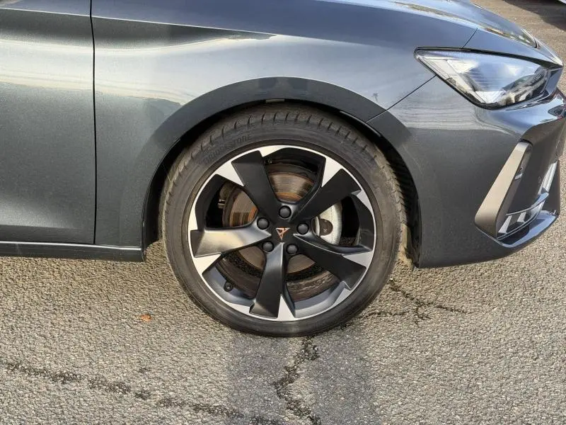 Gros plan sur la roue avant droite du SEAT LEON 1.5 eTSI Hybrid 2025 en Gris Magnétique Métal avec jante noire et argent.