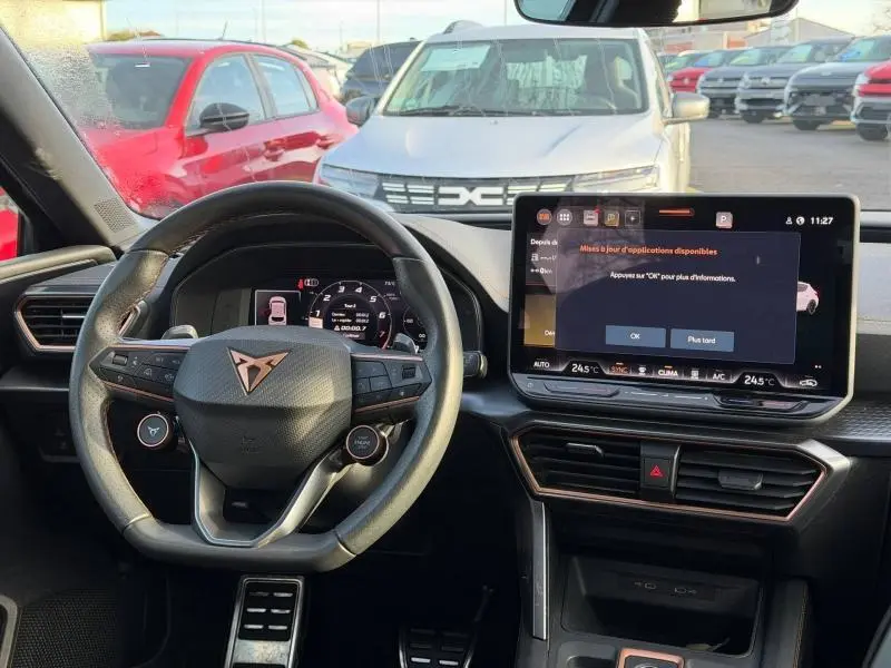 Vue intérieure du poste de conduite du SEAT LEON 2025 hybride, avec volant multifonction et écran tactile central allumé.