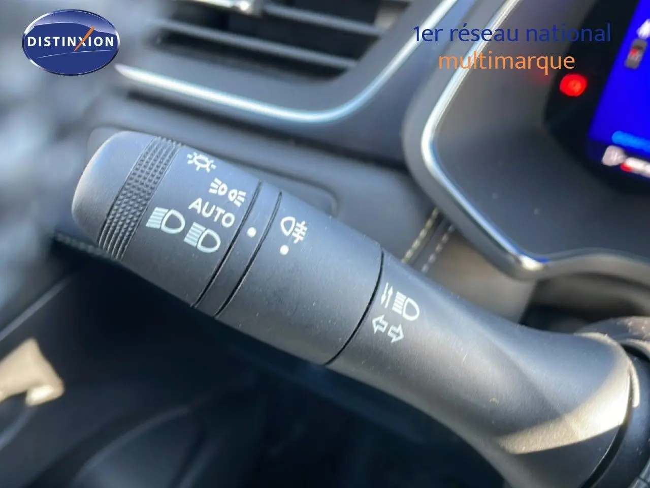 Gros plan sur la commande des phares et clignotants du Renault Symbioz 2025, intérieur noir avec écran tactile visible.