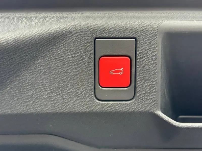 Bouton rouge d'ouverture électrique du hayon sur la garniture intérieure d'un Peugeot 5008 Hybrid blanc Okénite.