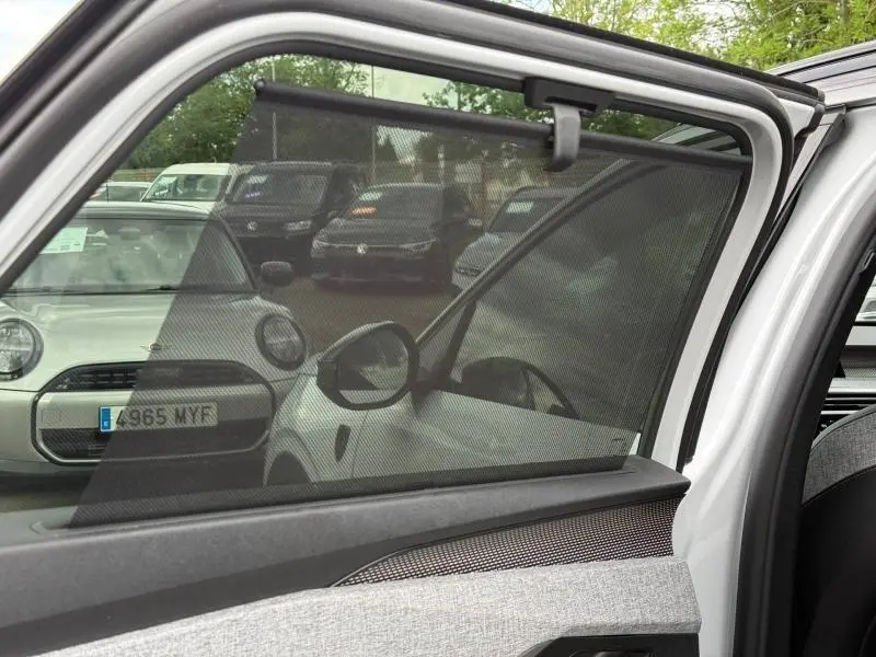 Vue partielle côté gauche à travers la porte ouverte d’un Peugeot 5008 Hybrid blanc Okénite avec pare-soleil intégré.