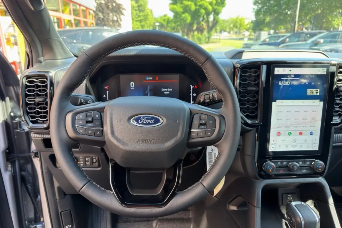 Vue intérieure centrée sur le volant cuir multifonctions et l'écran tactile vertical du Ford Ranger gris iconic 2026.