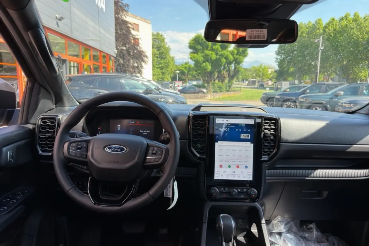 Vue intérieure frontale du Ford Ranger gris iconic, avec volant cuir multifonctions et grand écran tactile vertical central.