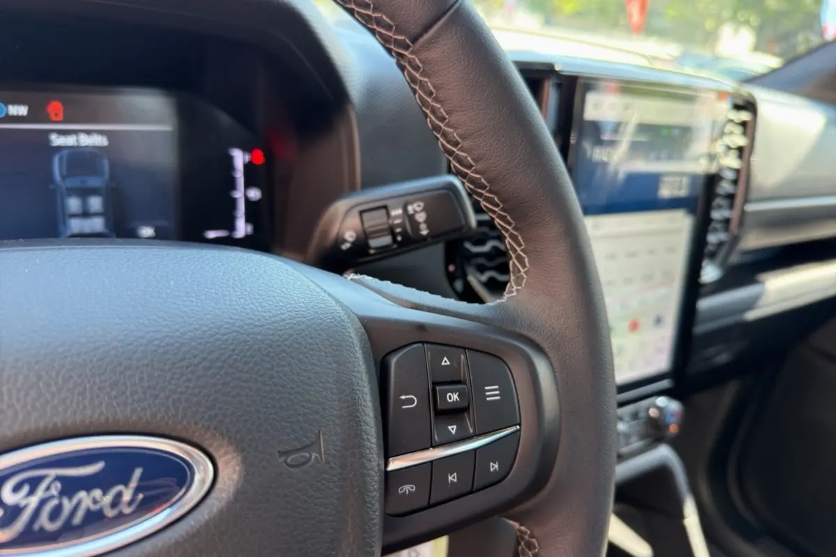 Gros plan sur le volant cuir multifonctions du Ford Ranger 2026, avec tableau de bord numérique et écran tactile vertical.