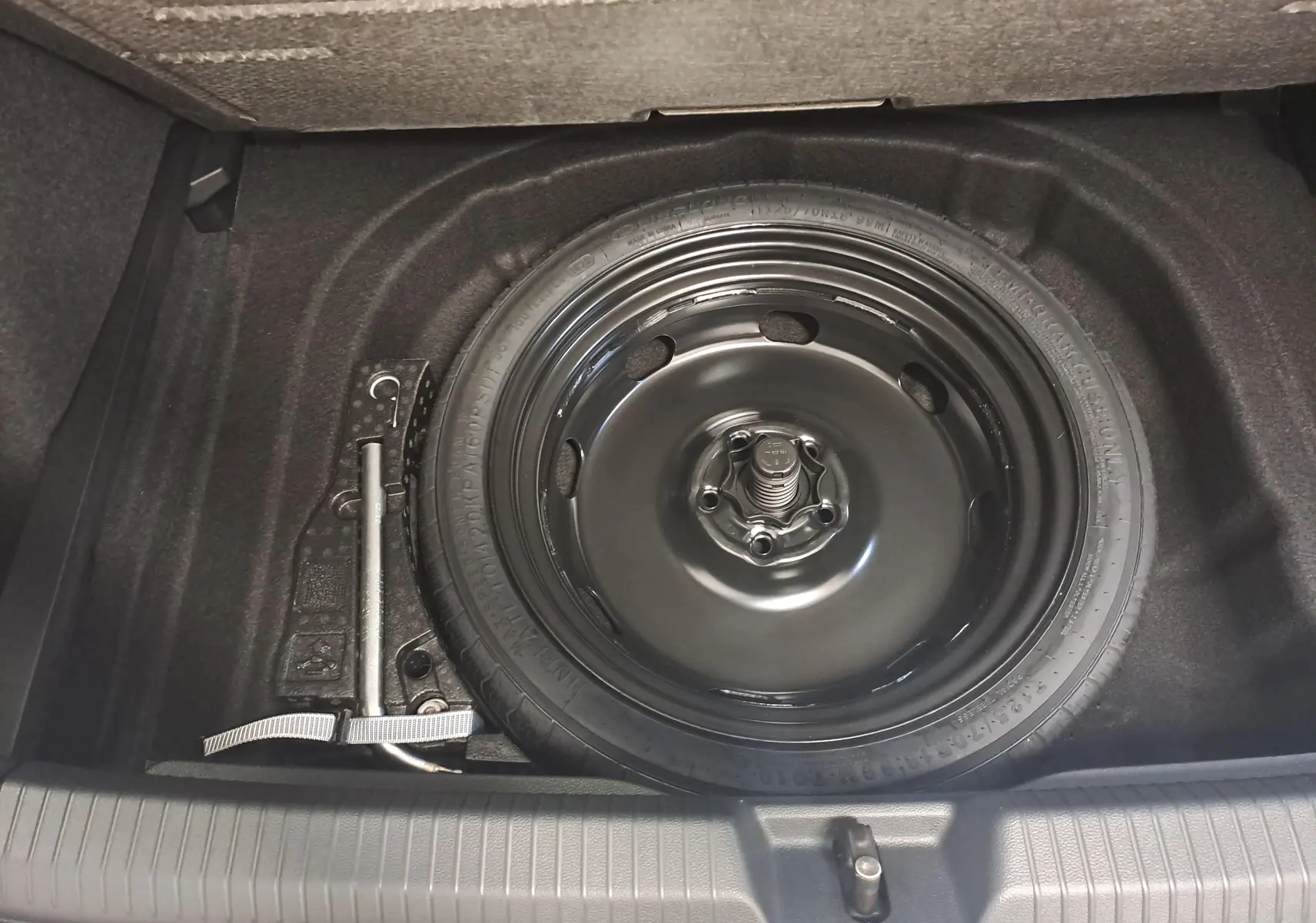 Roue de secours à encombrement réduit avec cric dans le coffre d'une Volkswagen Golf 2.0 TDI blanc Oryx nacré.
