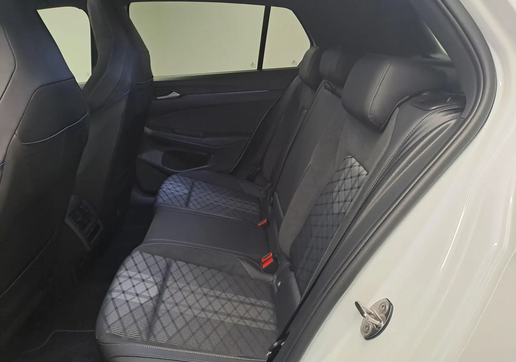 Vue intérieure côté droit des sièges arrière en cuir et tissu gris à motifs de la Volkswagen Golf 2025 Blanc Oryx nacré.