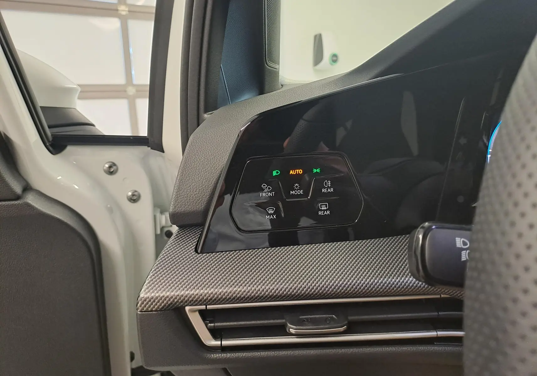 Détail du tableau de bord côté gauche d’une Volkswagen Golf blanc Oryx nacré, avec commandes d’éclairage et ventilation visibles.
