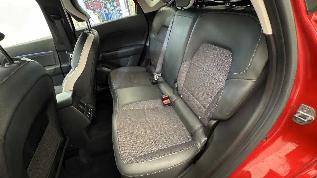 Vue intérieure arrière côté droit du Renault Captur rouge 2024, sièges mixtes tissu et cuir noir.