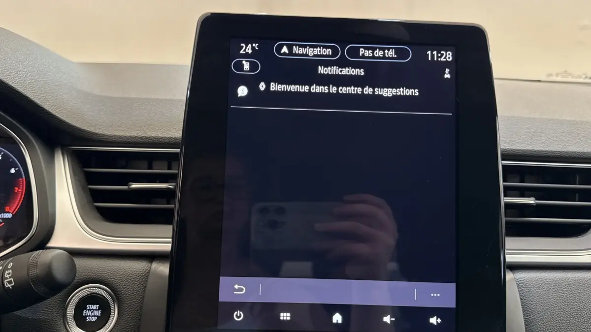 Écran tactile central allumé dans l'habitacle du Renault Captur rouge, affichant le menu de navigation.