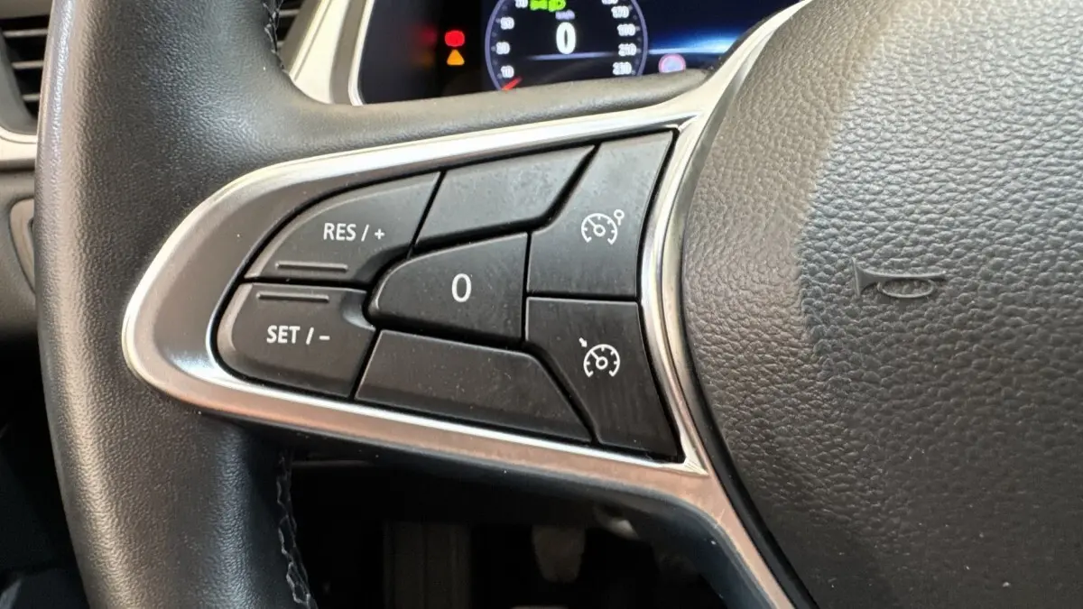 Gros plan sur les commandes de régulateur de vitesse au volant noir du Renault Captur Techno TCe 90 2024.