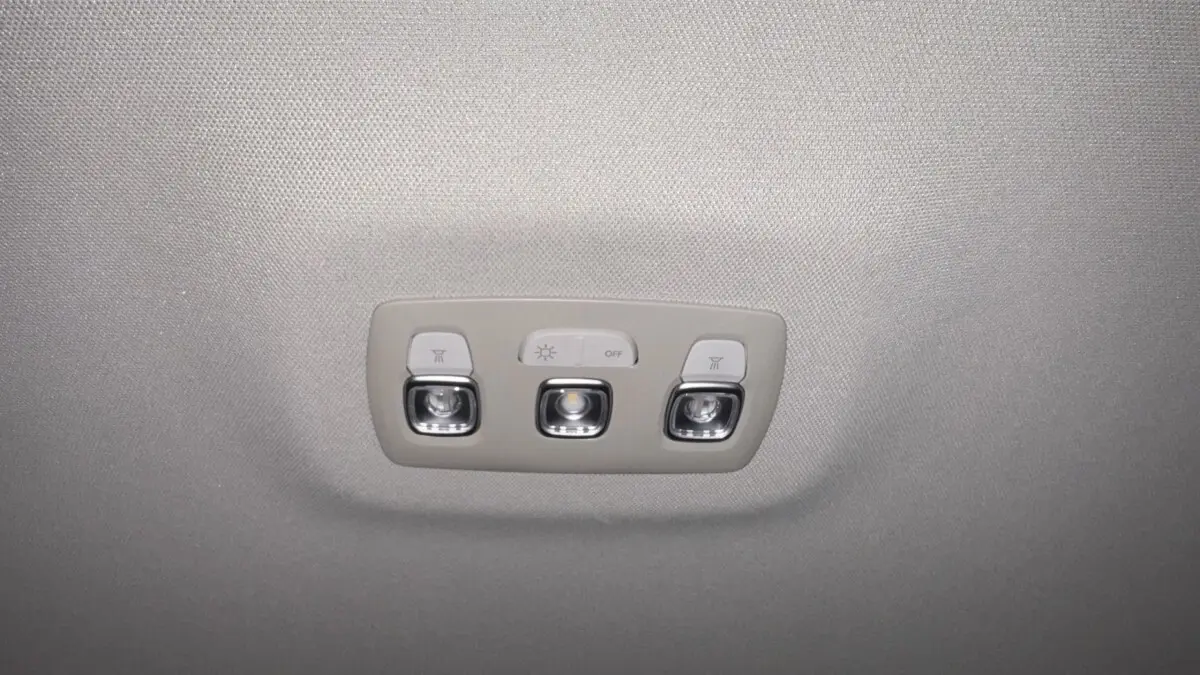 Plafonnier intérieur gris avec trois boutons lumineux dans un Renault Captur rouge vue de dessous.