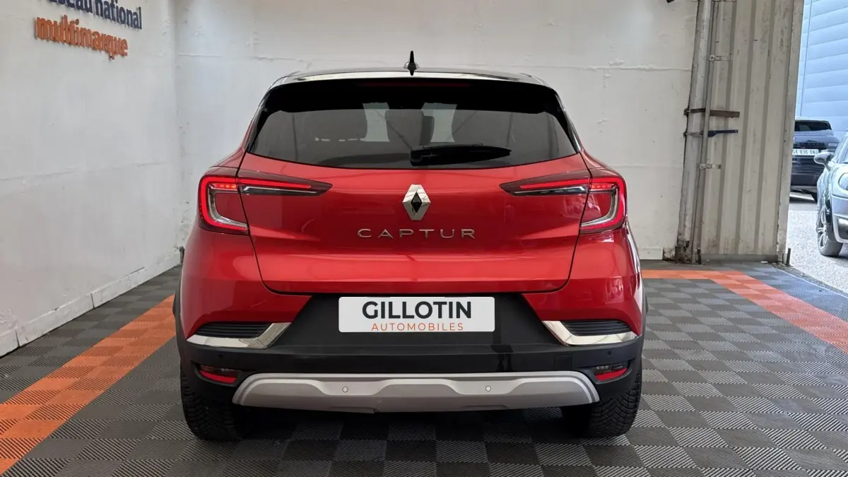 Vue arrière d'un Renault Captur rouge 2024 avec feux LED et logo centré sur un sol à damiers noir et orange.