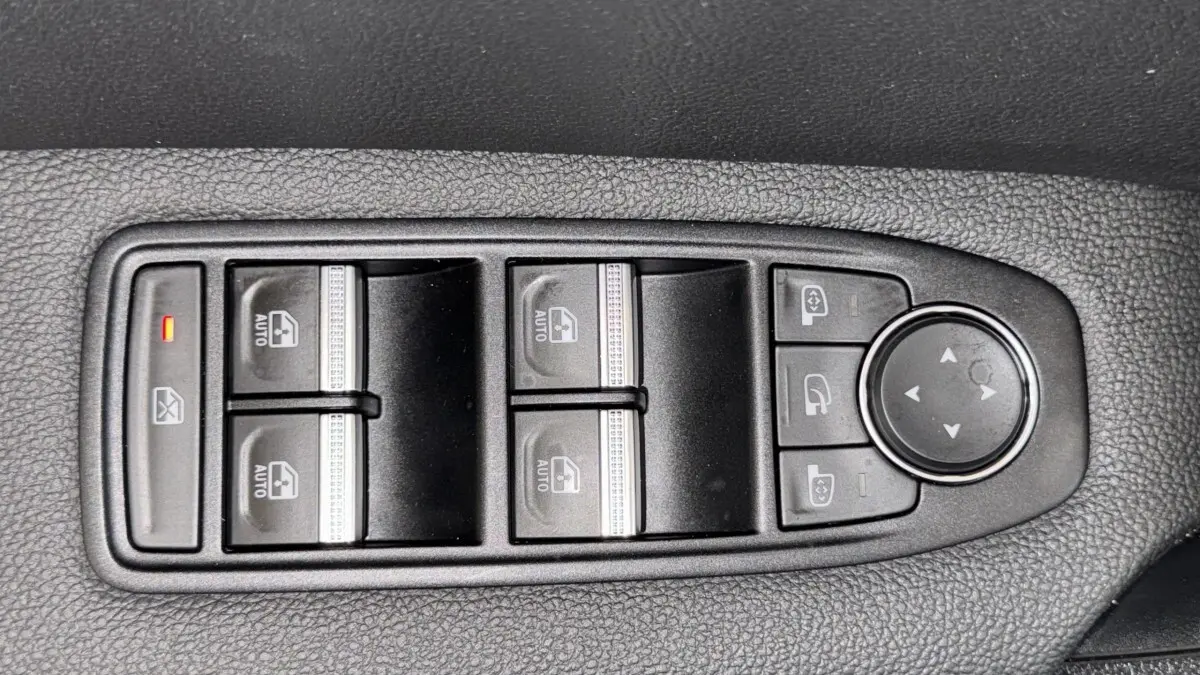 Gros plan sur les commandes de lève-vitres et rétroviseurs côté conducteur du Renault Captur rouge 2024.