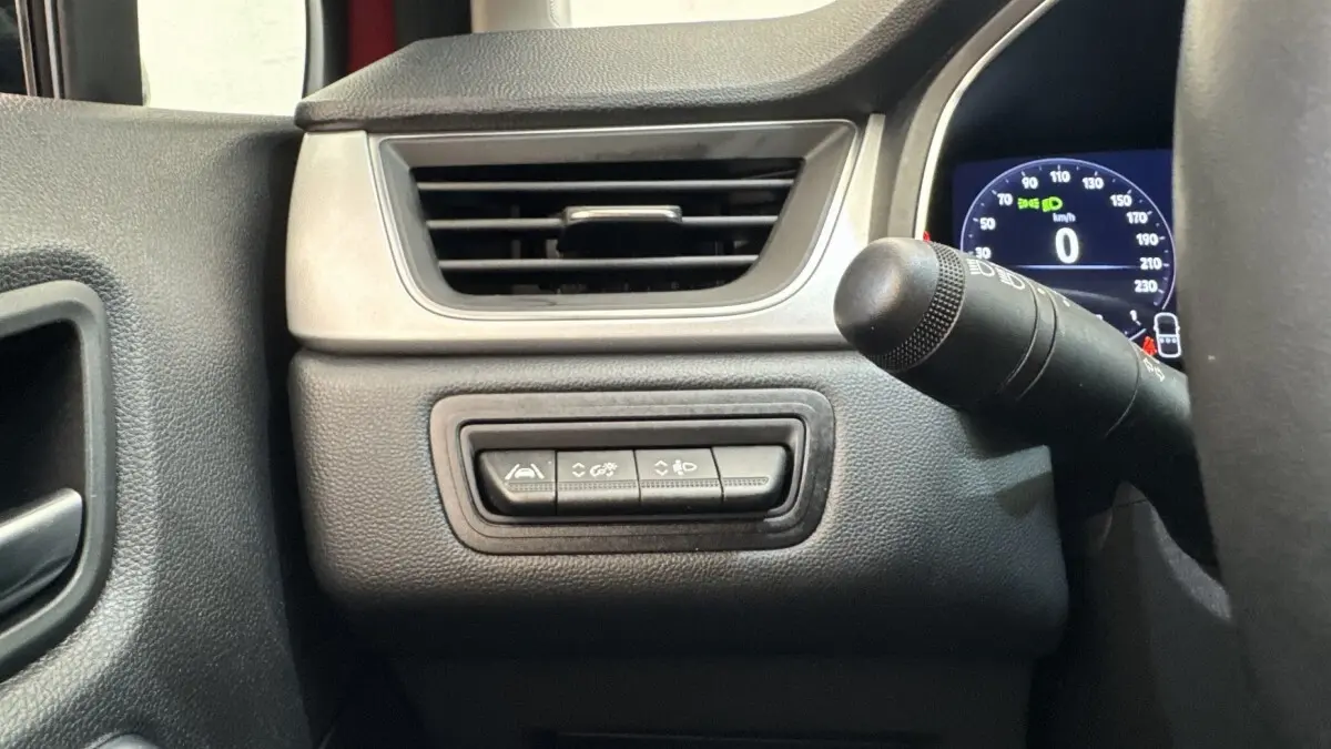 Détail intérieur côté gauche du tableau de bord du Renault Captur rouge 2024 avec commandes d'assistance et affichage numérique.