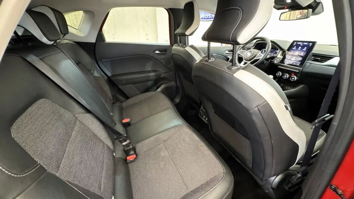 Intérieur arrière du Renault Captur Techno rouge 2024, vue côté gauche avec sièges bi-matière et écran tactile central visible.
