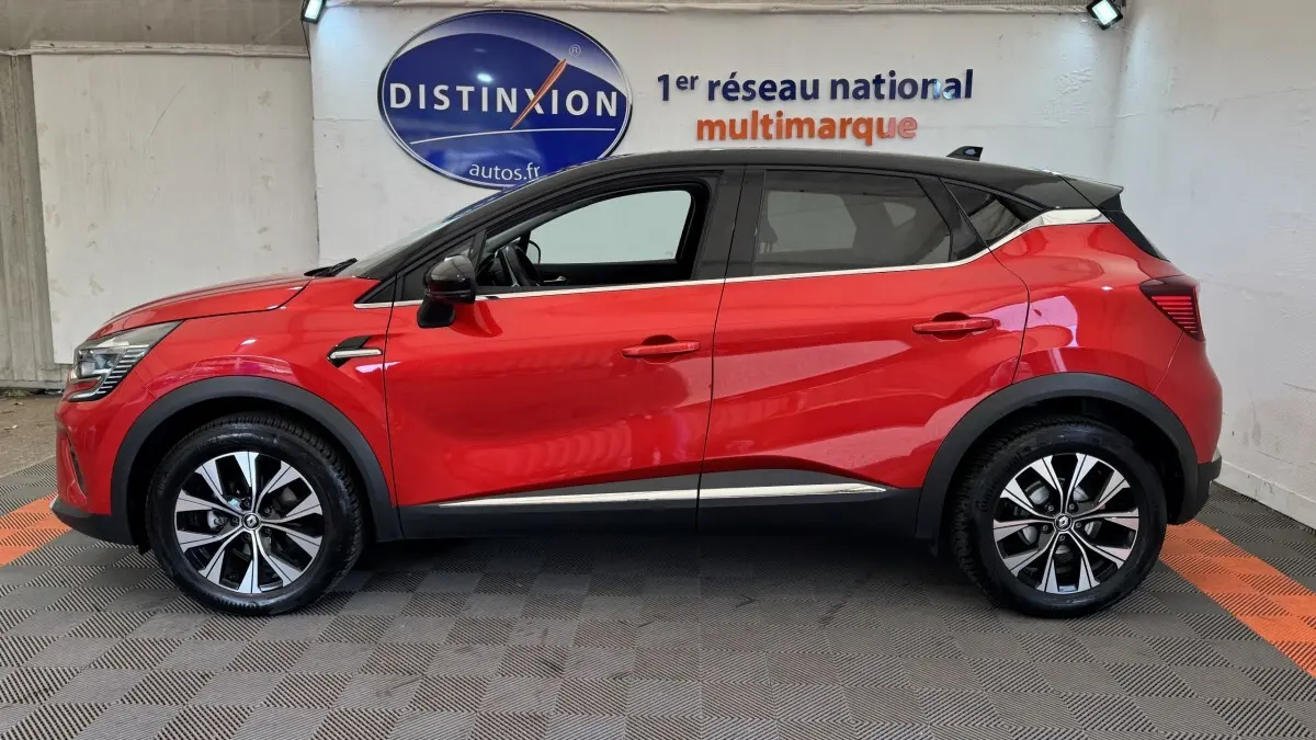 Profil droit du Renault Captur Techno TCe 90 rouge 2024 avec toit noir et jantes alliage bicolores.