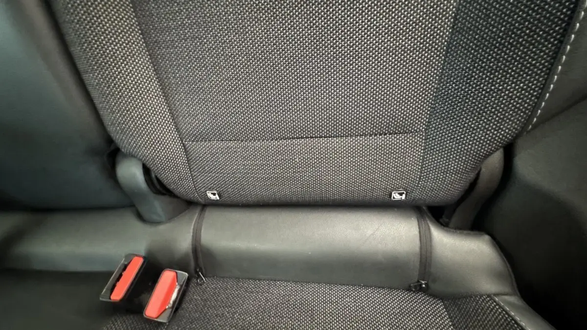 Détail de la banquette arrière noire du Renault Captur 2024, montrant les attaches Isofix et les boucles de ceinture rouges.