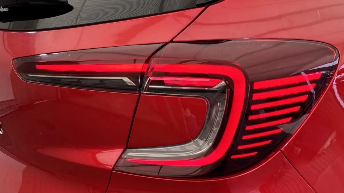 Gros plan sur le feu arrière droit rouge du Renault Captur 2024 finition techno TCe 90, carrosserie rouge.
