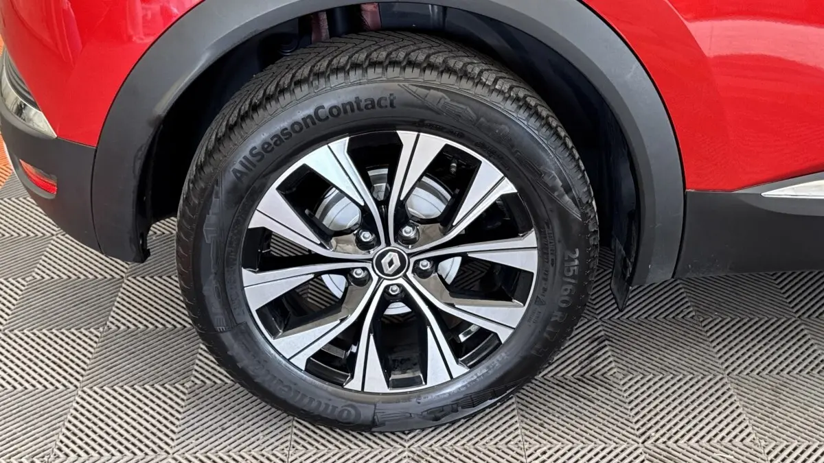 Gros plan sur la roue avant droite du Renault Captur rouge 2024 avec jante alliage bicolore et logo Renault central.