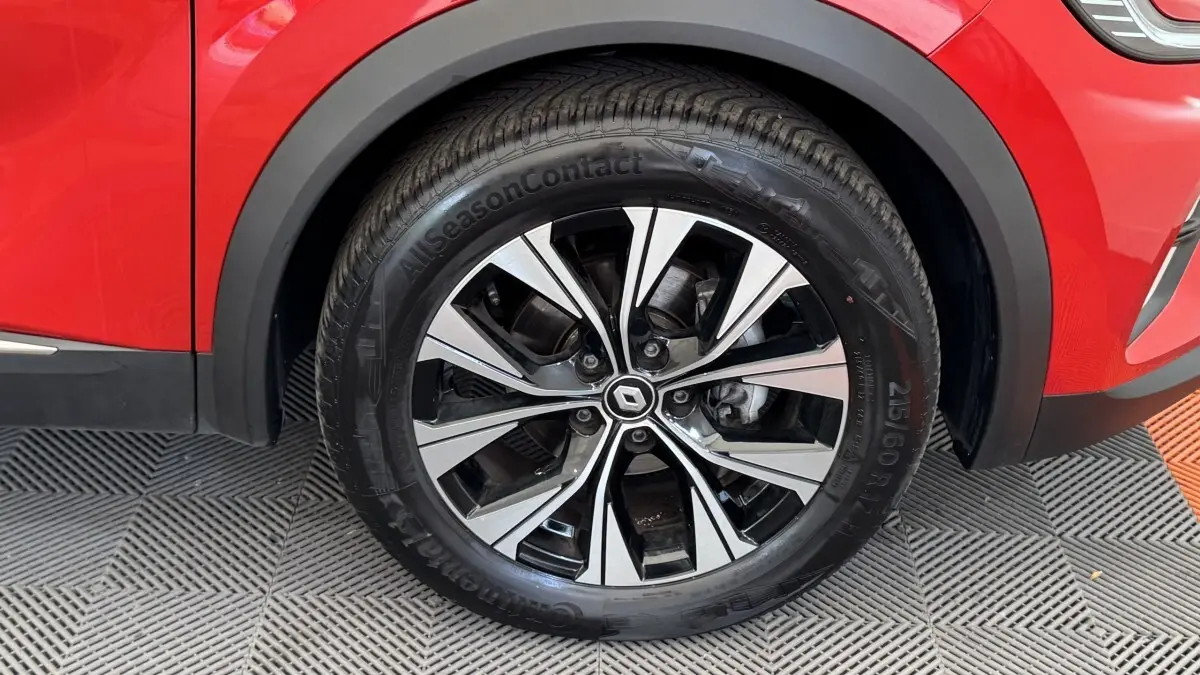 Gros plan sur la roue avant droite d’un Renault Captur rouge 2024 avec jante alliage bicolore et pneu toutes saisons.
