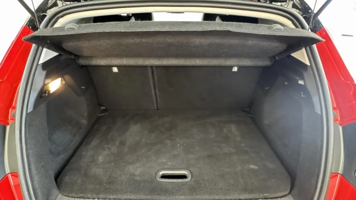 Coffre ouvert vu de l'arrière d'un Renault Captur rouge 2024, espace de chargement vide et tapis noir.