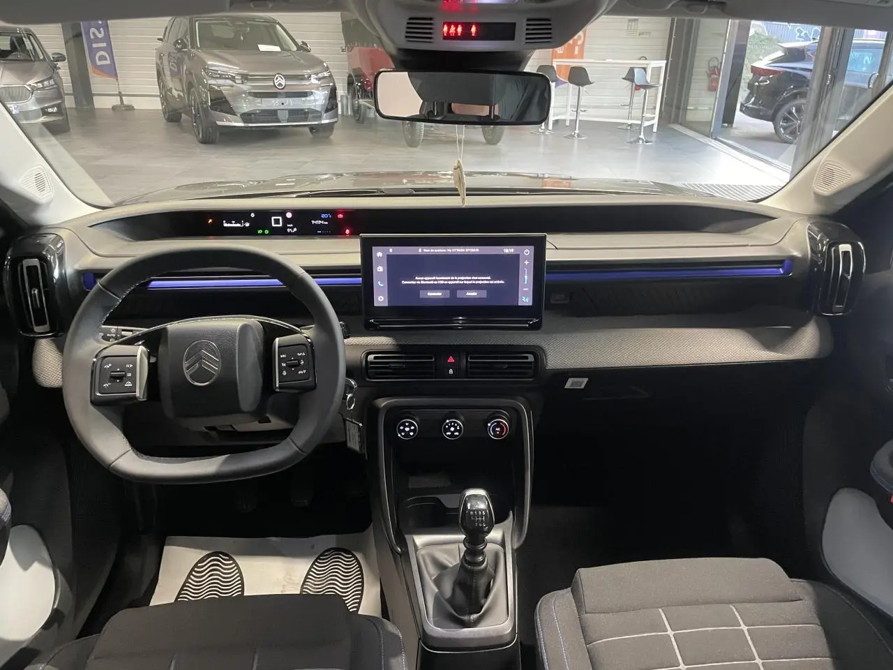 Vue intérieure avant du tableau de bord et volant de la Citroën C3 gris foncé avec écran tactile central et boîte manuelle.