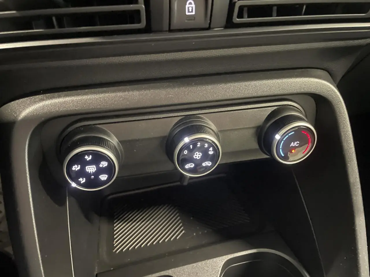 Gros plan sur les commandes de climatisation manuelle de la Citroën C3 2025, boutons noirs avec éclairage blanc.