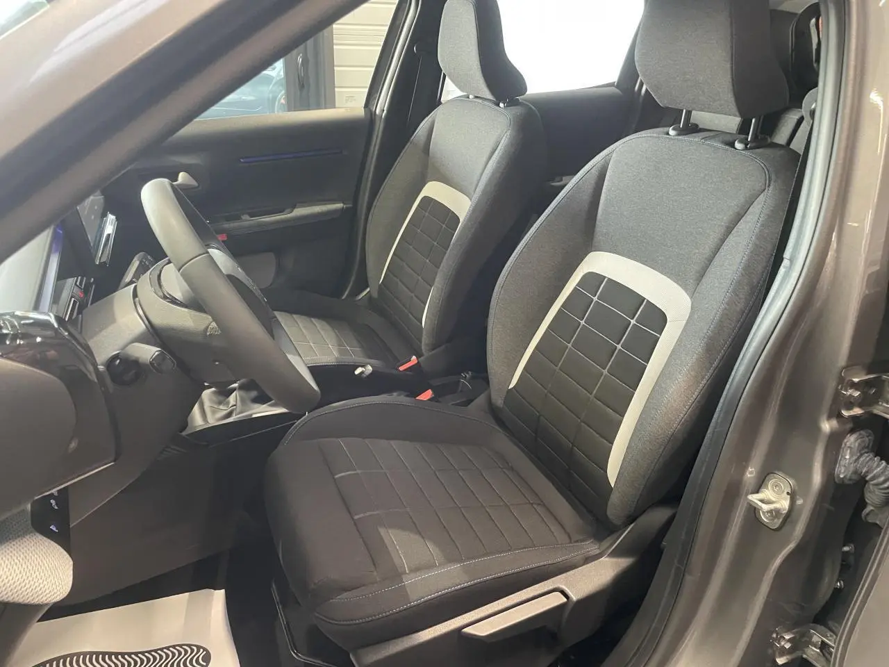 Vue intérieure côté conducteur de la Citroën C3 2025 gris foncé, sièges tissu noir avec inserts gris clair.