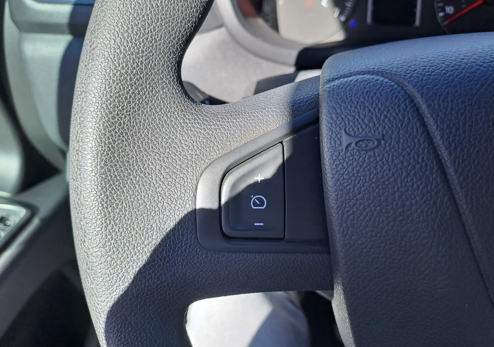 Gros plan sur le volant noir du Nissan Interstar 2024, montrant le bouton de réglage de l'éclairage côté gauche.