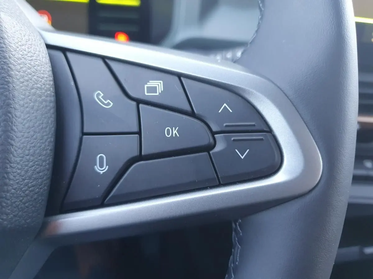 Gros plan sur les commandes multifonctions noires à droite du volant du Dacia Duster 2026 gris schiste.