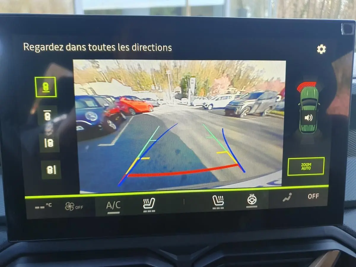 Vue de l'écran de caméra de recul du Dacia Duster 2026, montrant l'arrière et les lignes de guidage colorées.