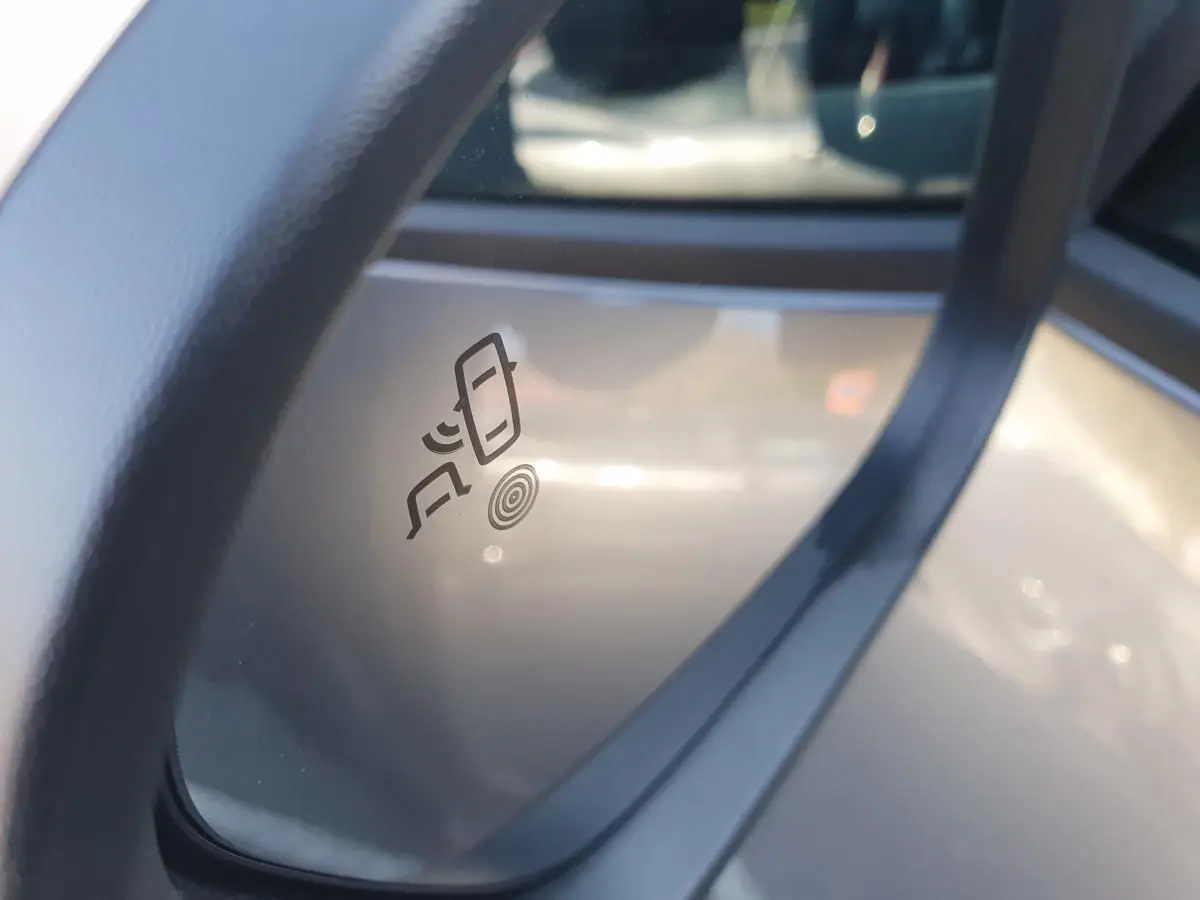 Détail du rétroviseur droit du Dacia Duster gris schiste 2026 avec icône d’alerte de changement de file.