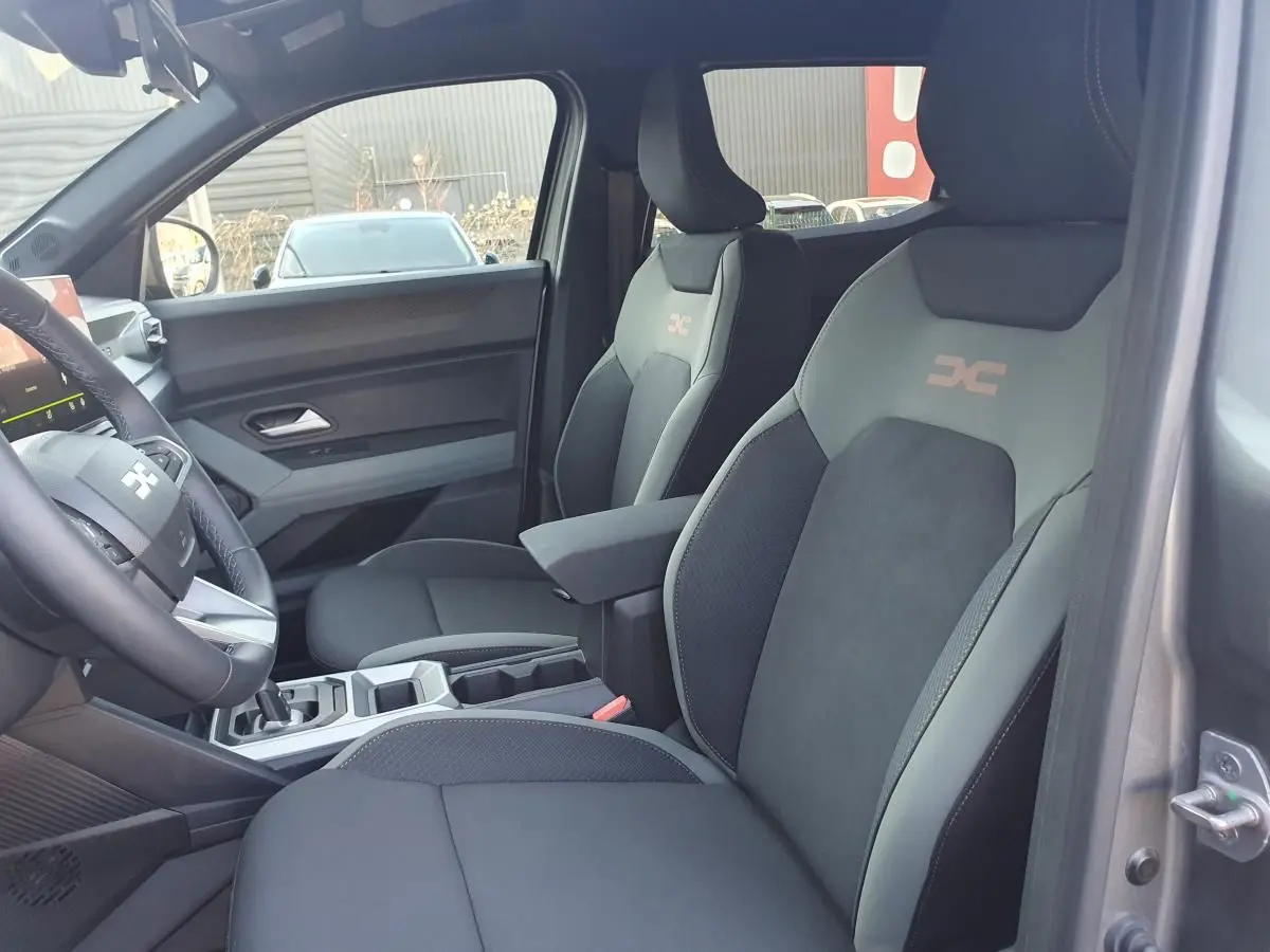 Vue intérieure côté droit du Dacia Duster 1.6 Hybrid gris schiste, sièges avant avec logo "Extreme" et accoudoir central.