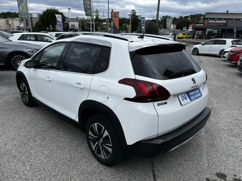 Peugeot 2008 blanc vue 3/4 arrière droit, avec vitres teintées et jantes alliage, stationné en extérieur.
