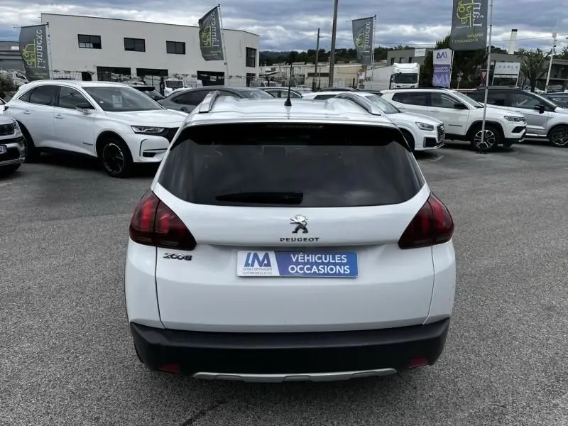 Vue arrière d’un Peugeot 2008 blanc de 2019 avec logo et plaque « Véhicules Occasions » sur un parking extérieur.