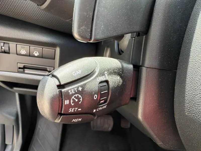 Gros plan sur la commande de régulateur de vitesse du Citroën C5 Aircross 2025, intérieur noir avec boutons visibles.