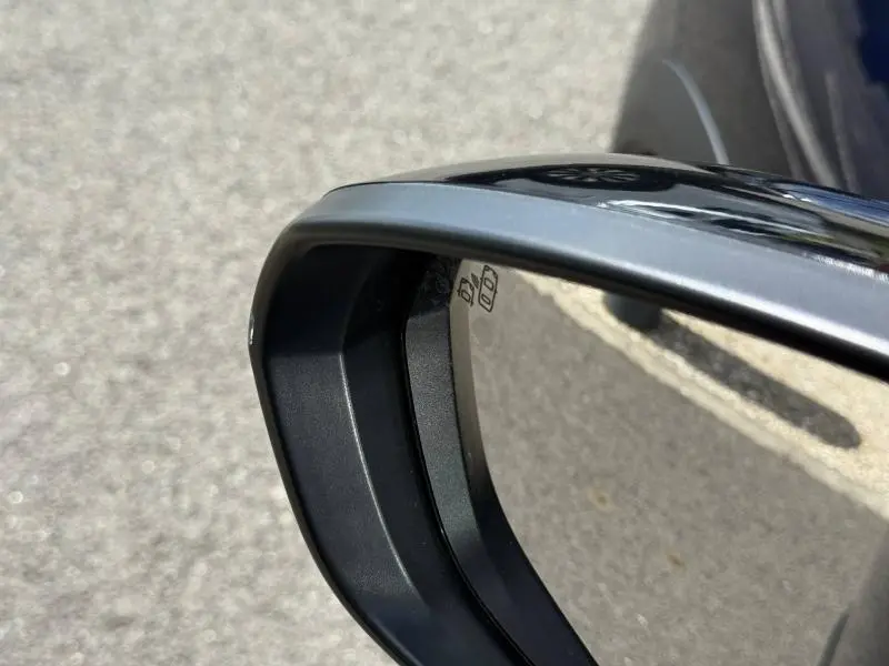 Gros plan sur le rétroviseur côté droit noir du Citroën C5 Aircross 2025 hybride essence, reflet de la route visible.