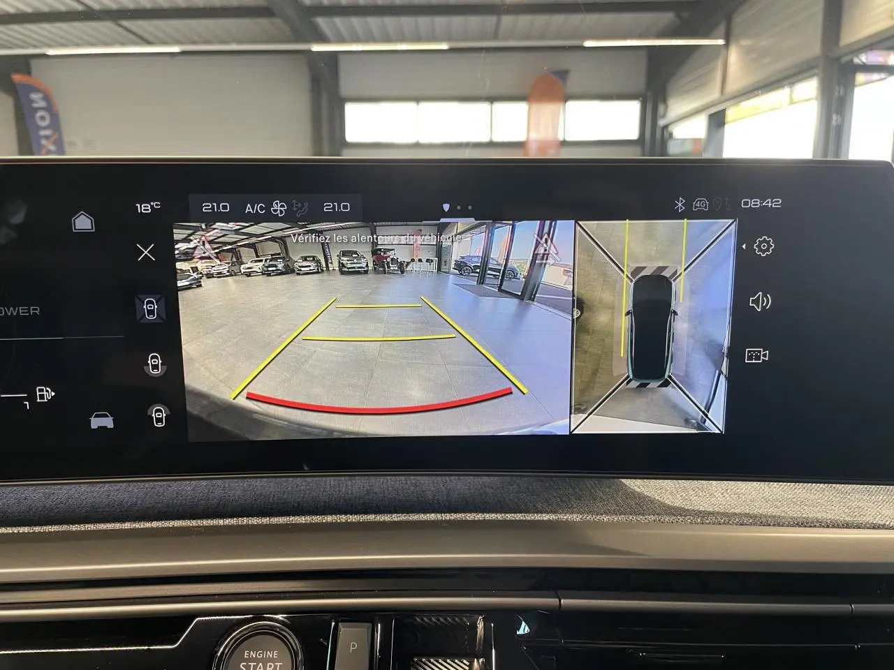 Écran intérieur du Peugeot 3008 montrant la caméra de recul et la vue 360 en garage lumineux.