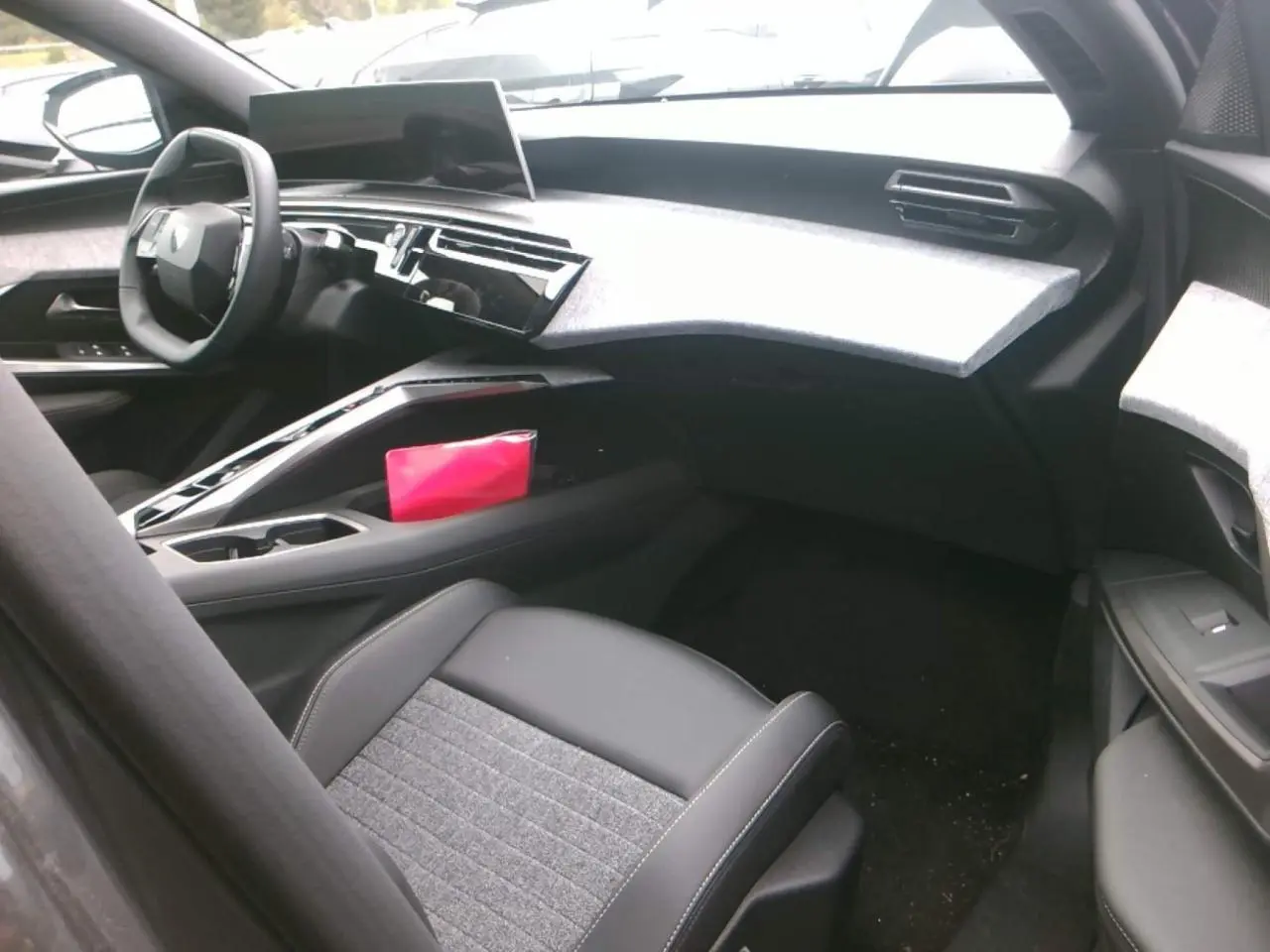 Intérieur avant droit du Peugeot 3008 2025 hybride, avec tableau de bord gris clair et sièges tissu et cuir noirs.
