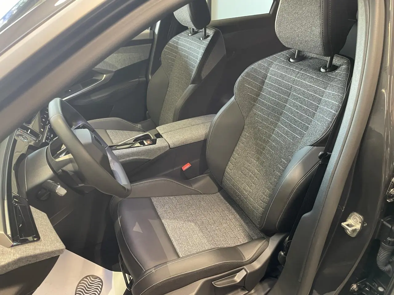 Vue intérieure côté conducteur du Peugeot 3008 2025 gris foncé, sièges tissu gris et cuir noir avec surpiqûres contrastées.