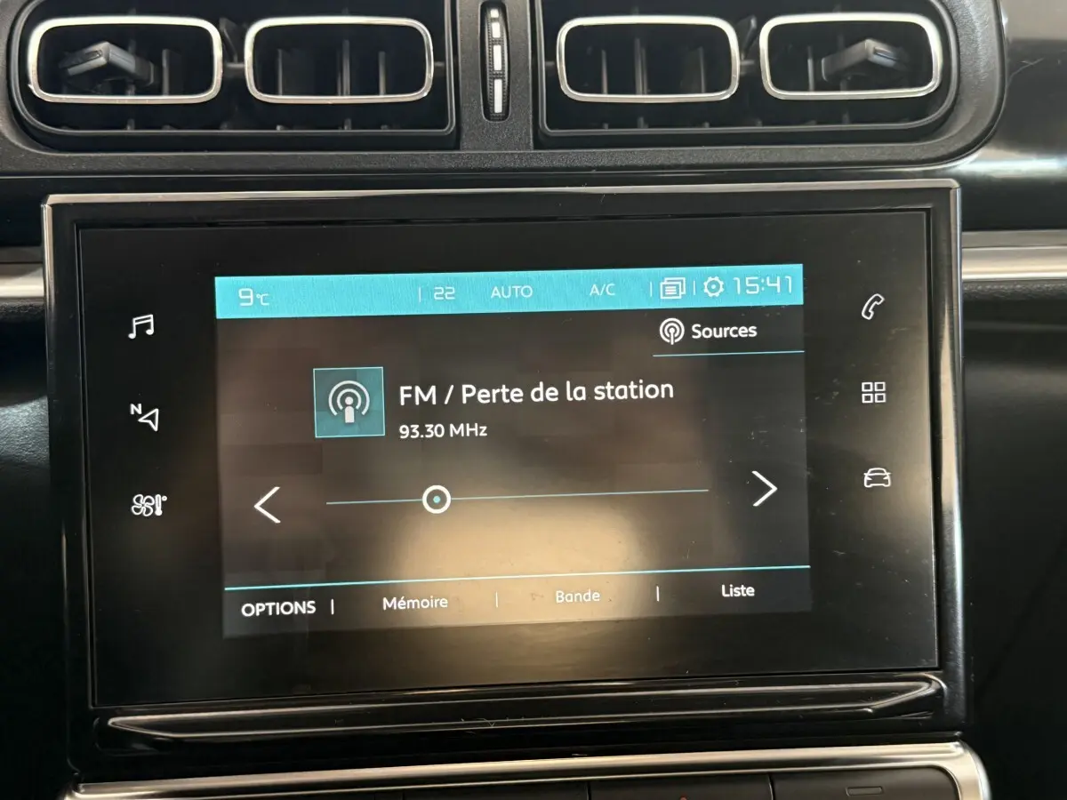 Écran tactile central affichant la radio FM dans l'habitacle noir d'une Citroën C3 gris clair, vue de face.