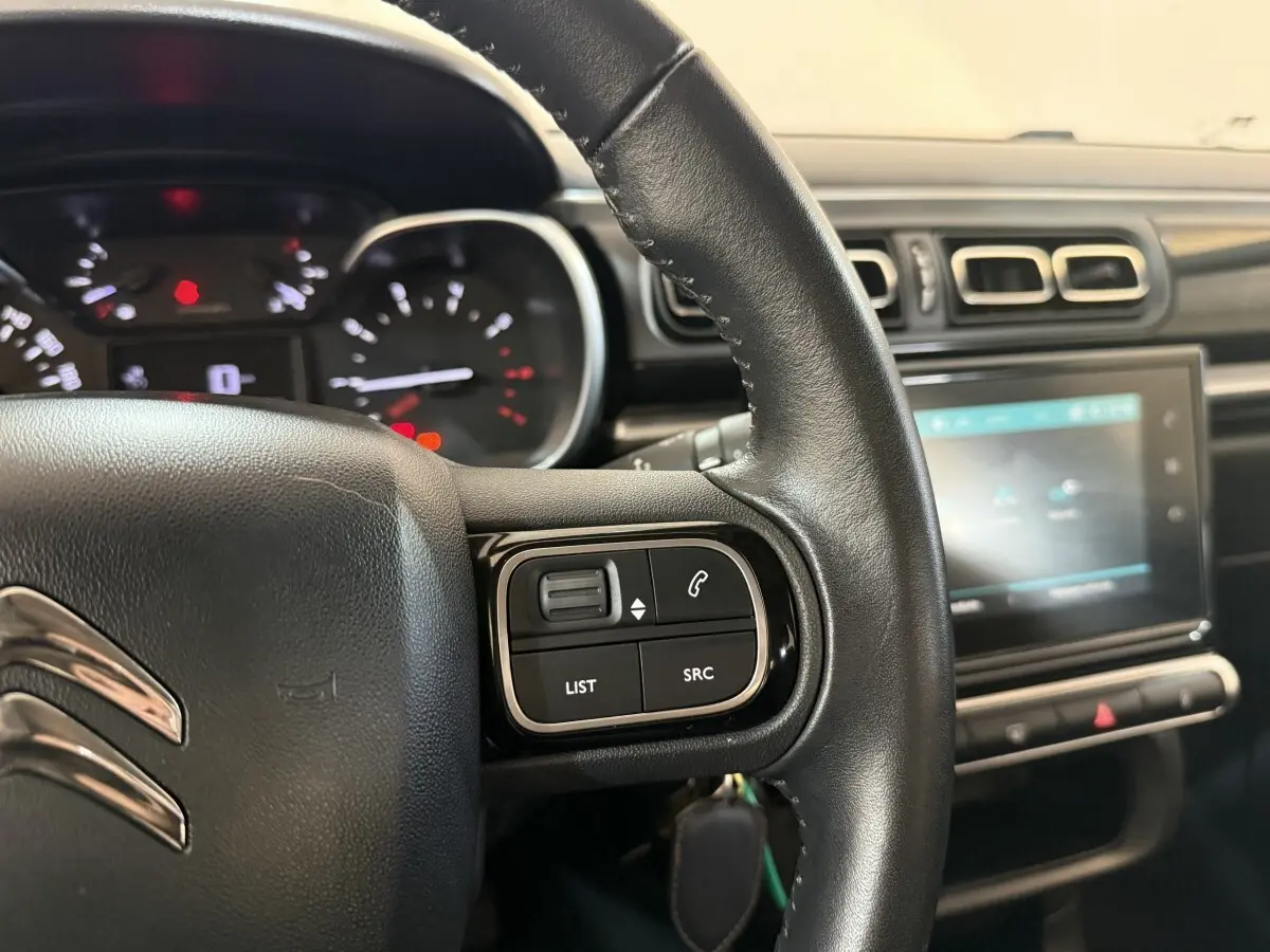 Gros plan sur le volant cuir et le tableau de bord tactile de la Citroën C3 gris clair, version Shine Business.