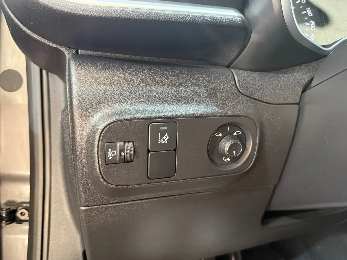 Vue du panneau de commandes côté gauche noir mat avec réglage phares et rétroviseurs d'une Citroën C3 gris clair 2019