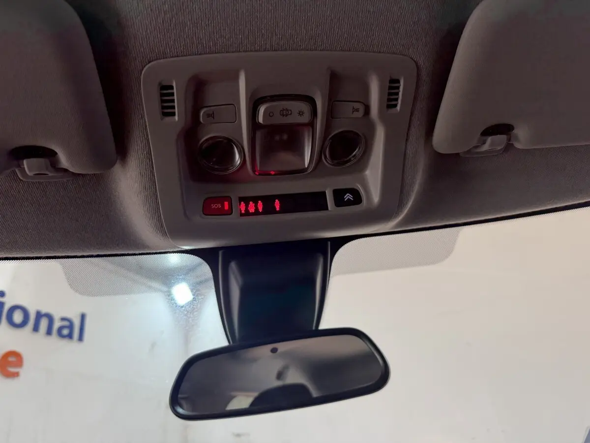 Vue intérieure du plafonnier et rétroviseur central de la Citroën C3 gris clair de 2019 avec commandes éclairage et SOS.