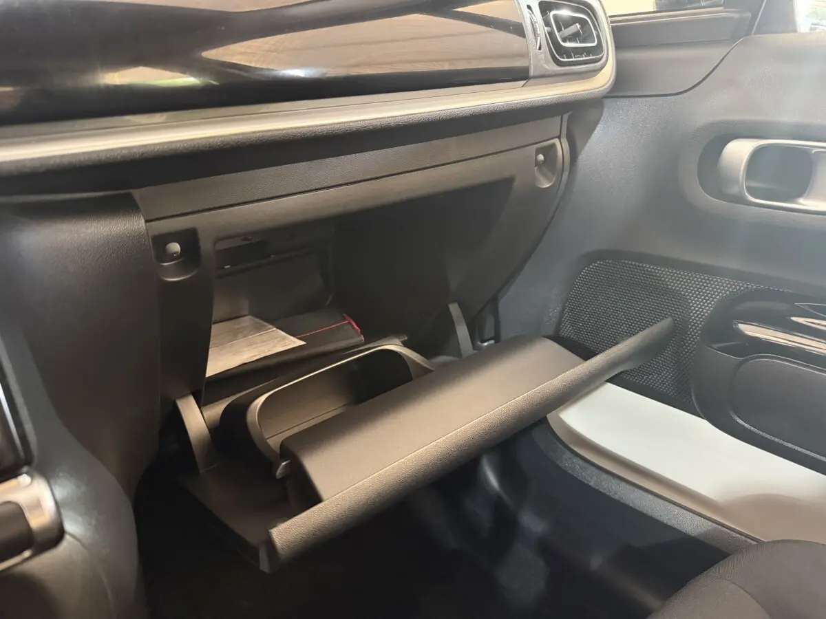 Intérieur de la Citroën C3 2019 gris clair, vue sur la boîte à gants ouverte côté passager avec tableau de bord noir.