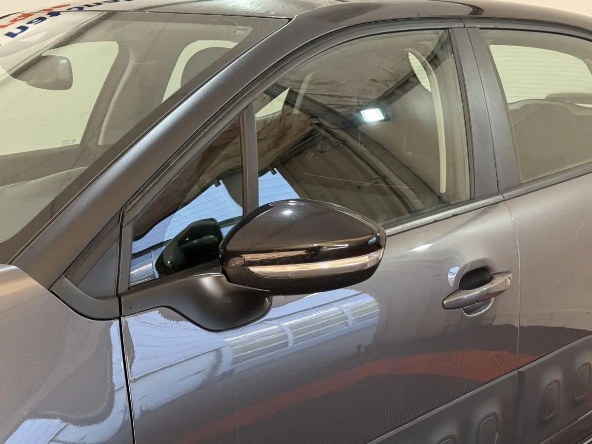 Vue côté gauche rapprochée d'une Citroën C3 gris clair avec rétroviseur noir brillant et poignées ton caisse.
