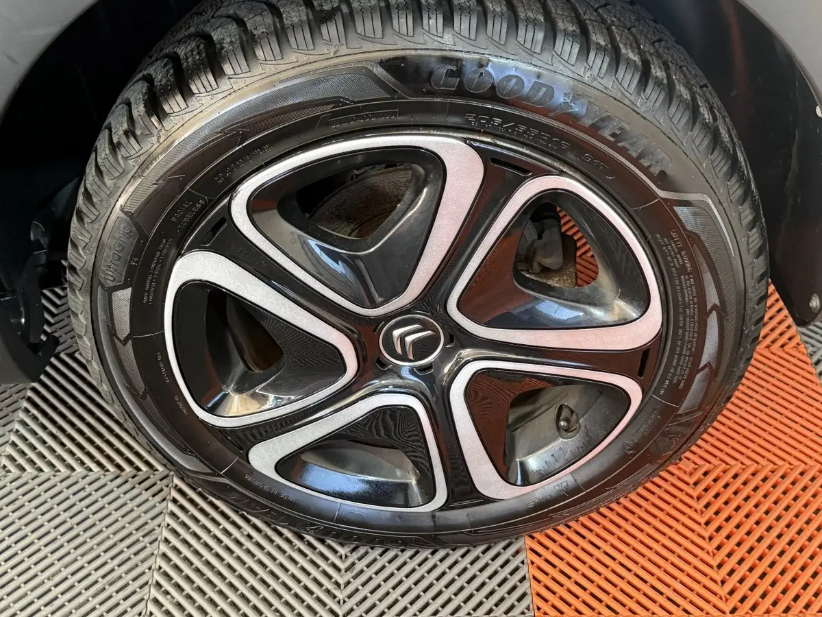 Gros plan sur la roue avant droite de la Citroën C3 gris clair avec jante alliage noire et argentée au logo Citroën.