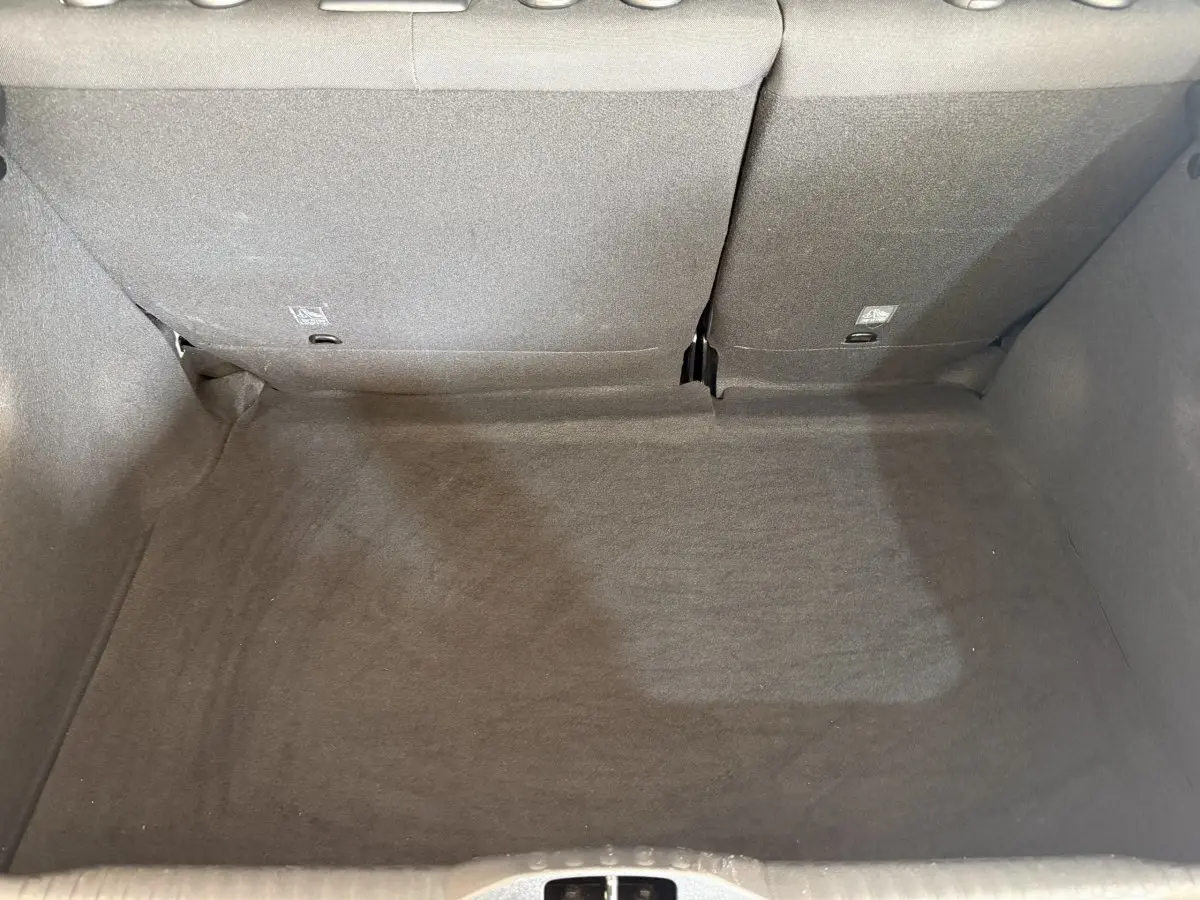 Vue plongeante sur le coffre spacieux et propre de la Citroën C3 gris clair avec banquette arrière rabattue.